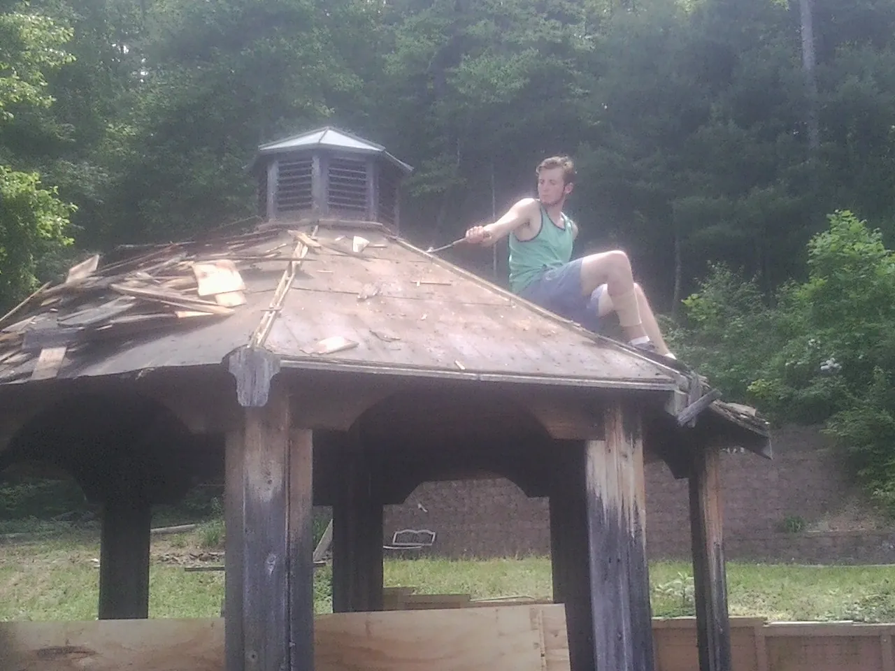 Tearing the old roof off a wooden gazebo before new shakes in Lake George