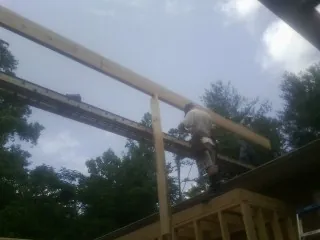 Carpenter setting a ridge beam over a new addition frame — Ice Dam Removal by Roofing Brothers in Lake George