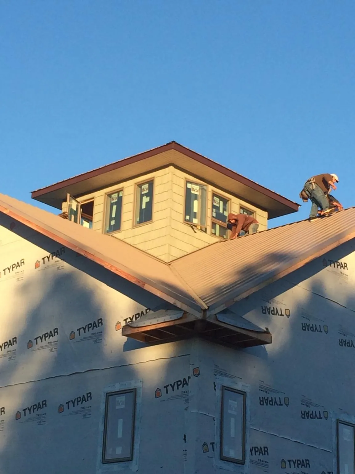 Roofers working around a rooftop cupola on a new metal roof at sunset — Roof Waterproofing in Lake George by Roofing Brothers